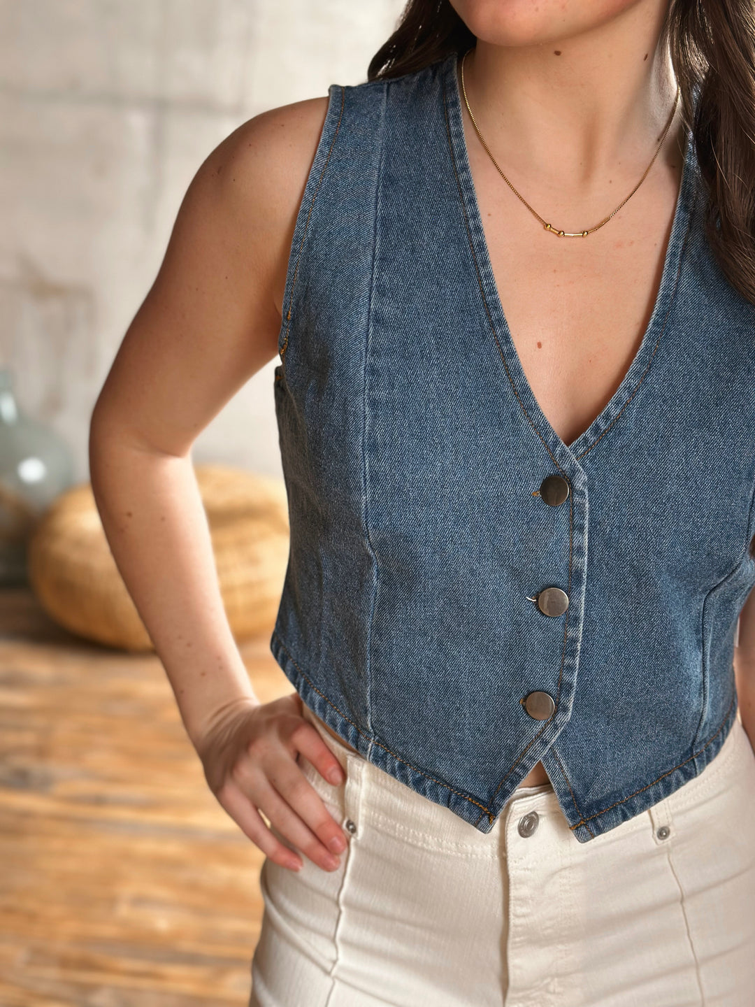 Woman wearing a denim vest with buttons and a blurred background.