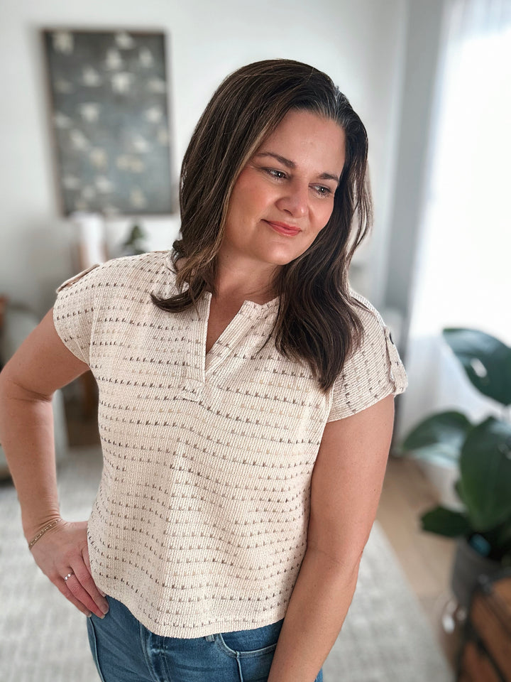 Woman wearing a beige patterned blouse in a home setting