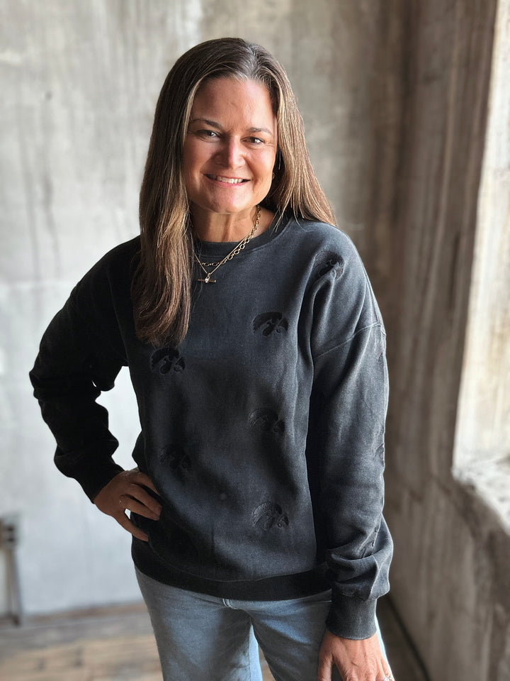 Woman wearing a dark gray sweatshirt standing indoors with a neutral background