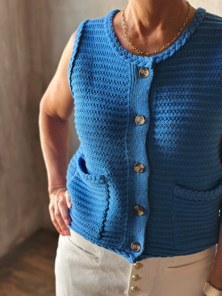 Front view solid blue sleeveless sweater knit vest, with a button front closure and functional front pockets. 