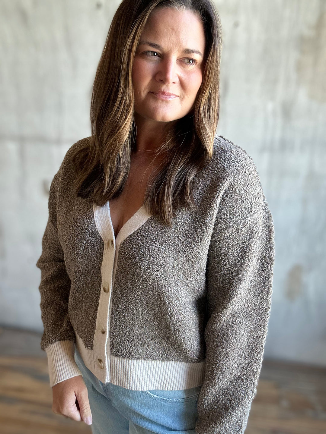 Woman wearing a brown speckled cardigan with cream cuffs, close-up