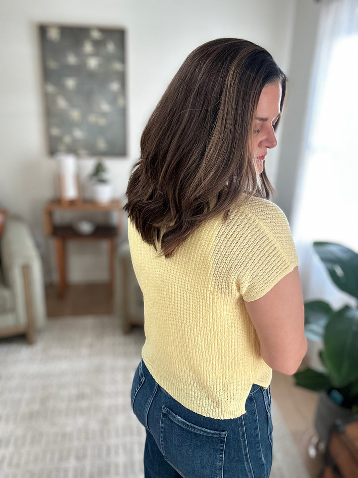 Woman wearing a yellow top and blue jeans in a living room setting