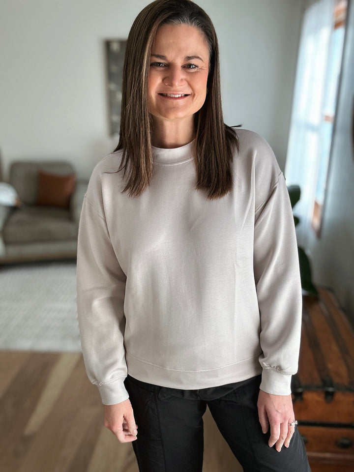 Woman wearing a light gray sweater in a living room setting