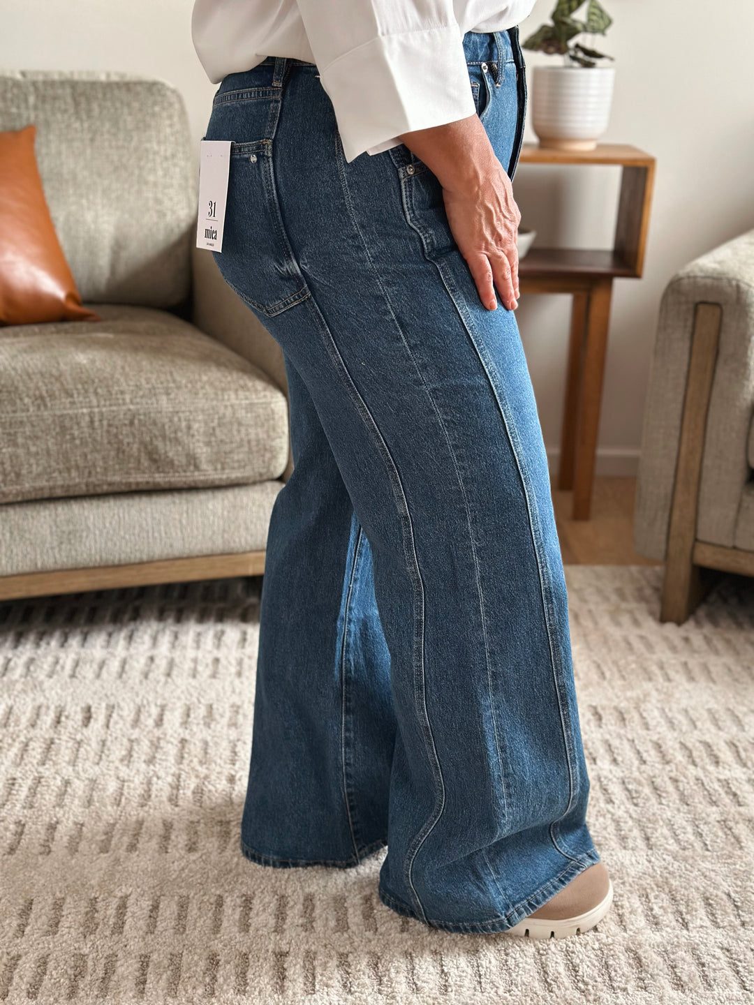 Person wearing blue jeans with a tag in a living room setting