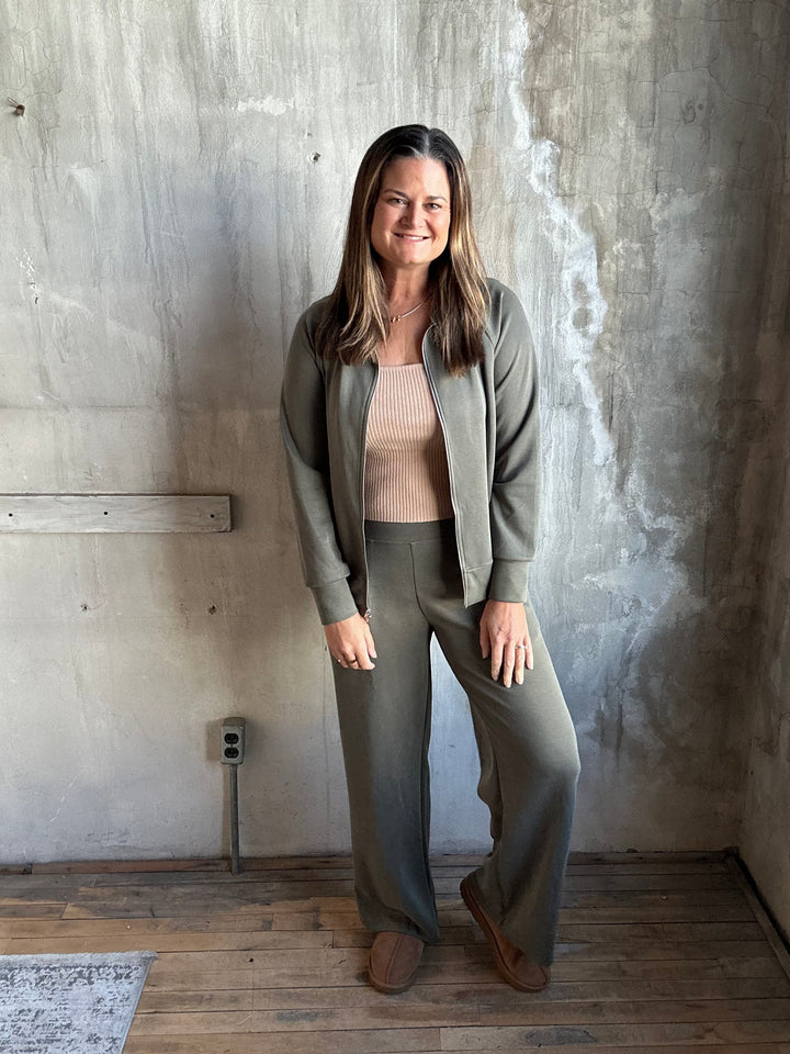 Woman wearing olive green wide-leg pants and a matching jacket, full-length view