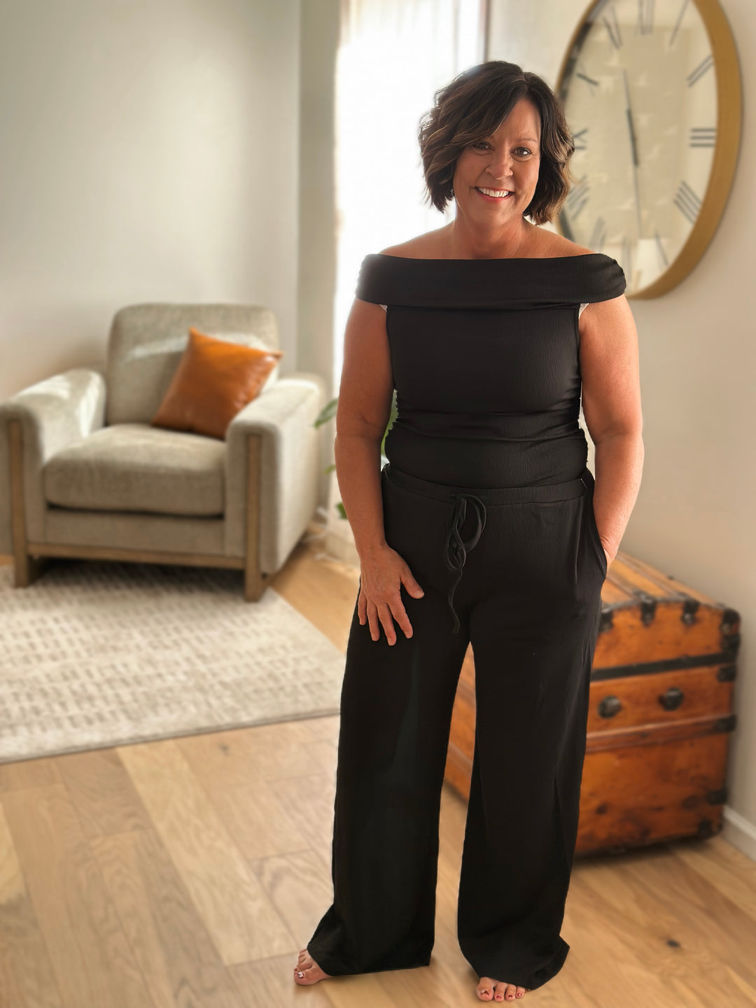 Woman wearing a black off-shoulder set in a living room.