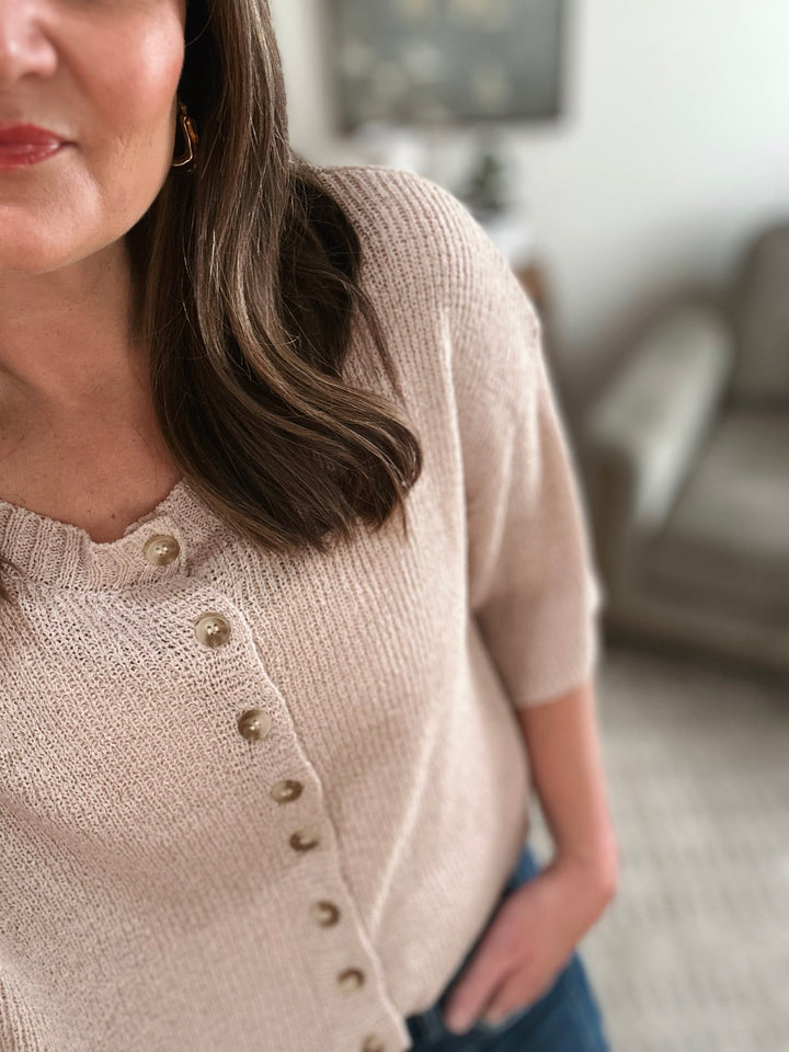 Woman wearing a beige cardigan in an indoor setting