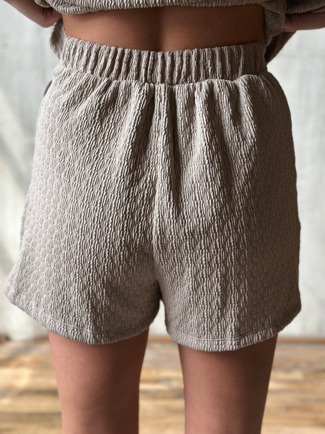 Person wearing textured gray shorts with a neutral background