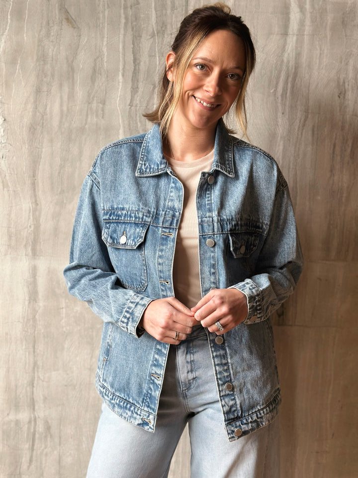 Woman wearing a denim jacket against a neutral wall