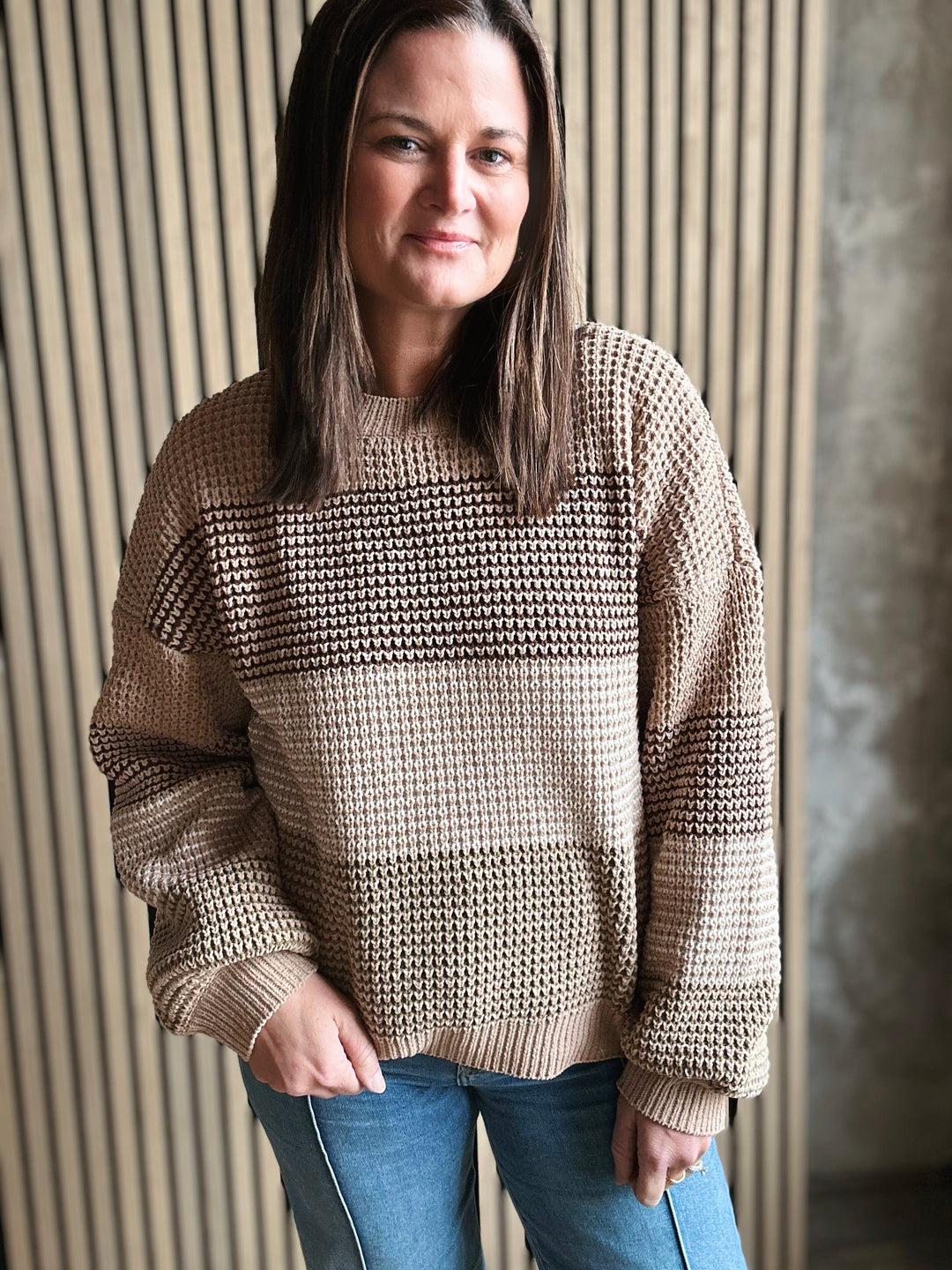 Woman wearing a beige textured sweater against a neutral background