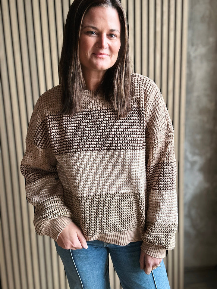 Woman wearing a beige textured sweater against a neutral background