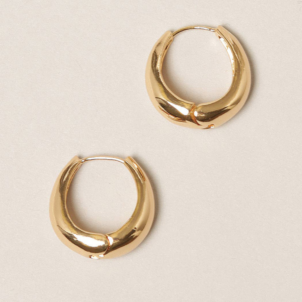 Gold hoop earrings on a beige background
