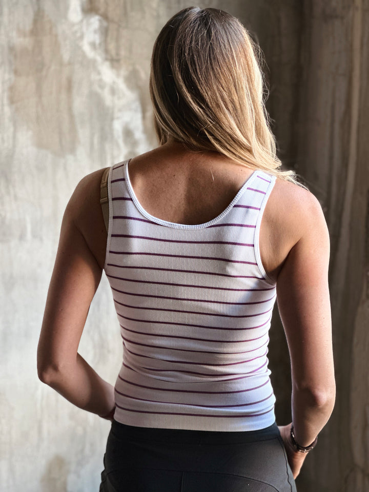 Person wearing a striped tank top with a neutral background