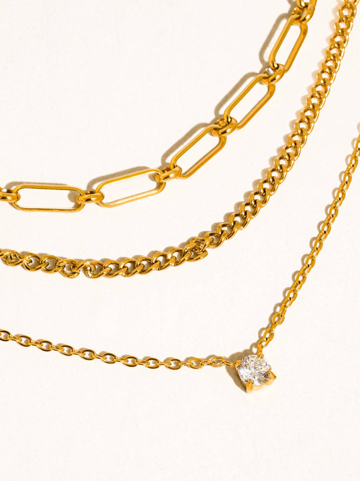 Three gold chain necklaces on a white background