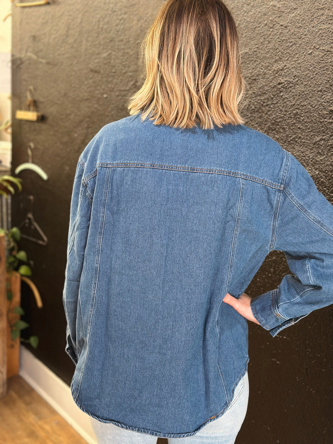 Person wearing a blue denim shirt with a blurred background
