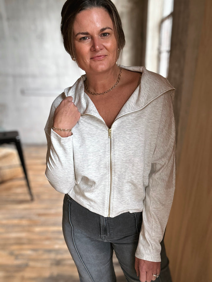 Woman wearing a light-colored zip-up hoodie in an indoor setting