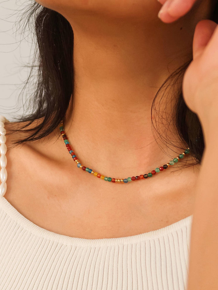 Close-up of a colorful beaded necklace on a person wearing a white top.