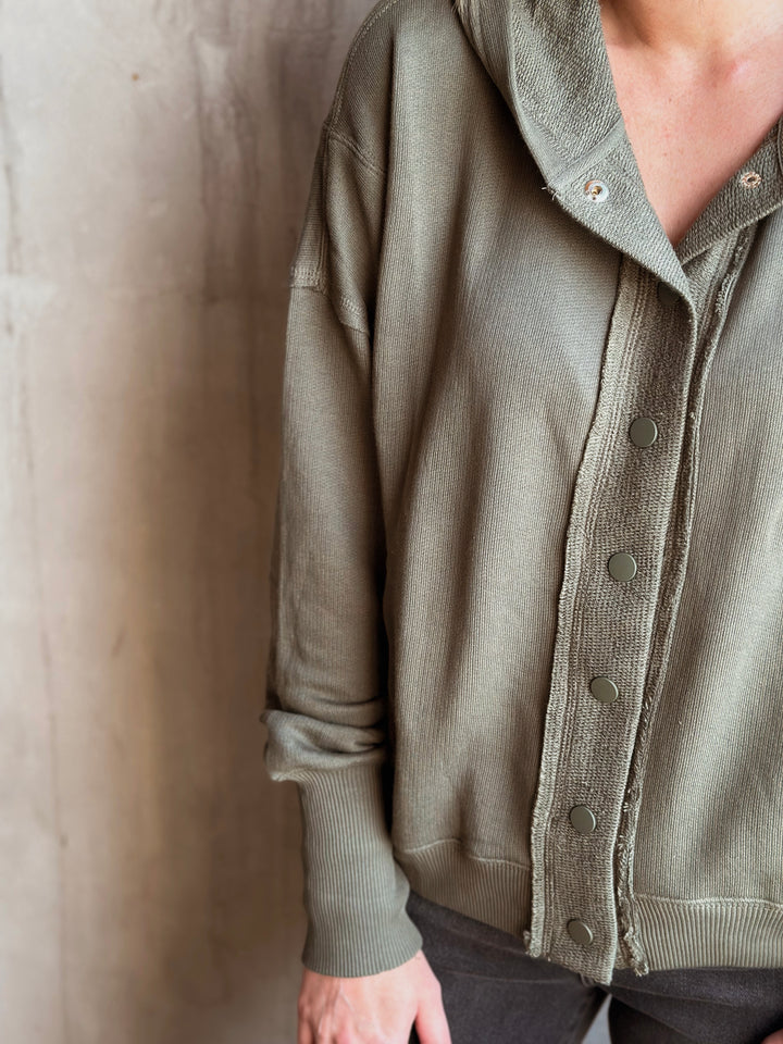 Person wearing a green cardigan against a neutral background
