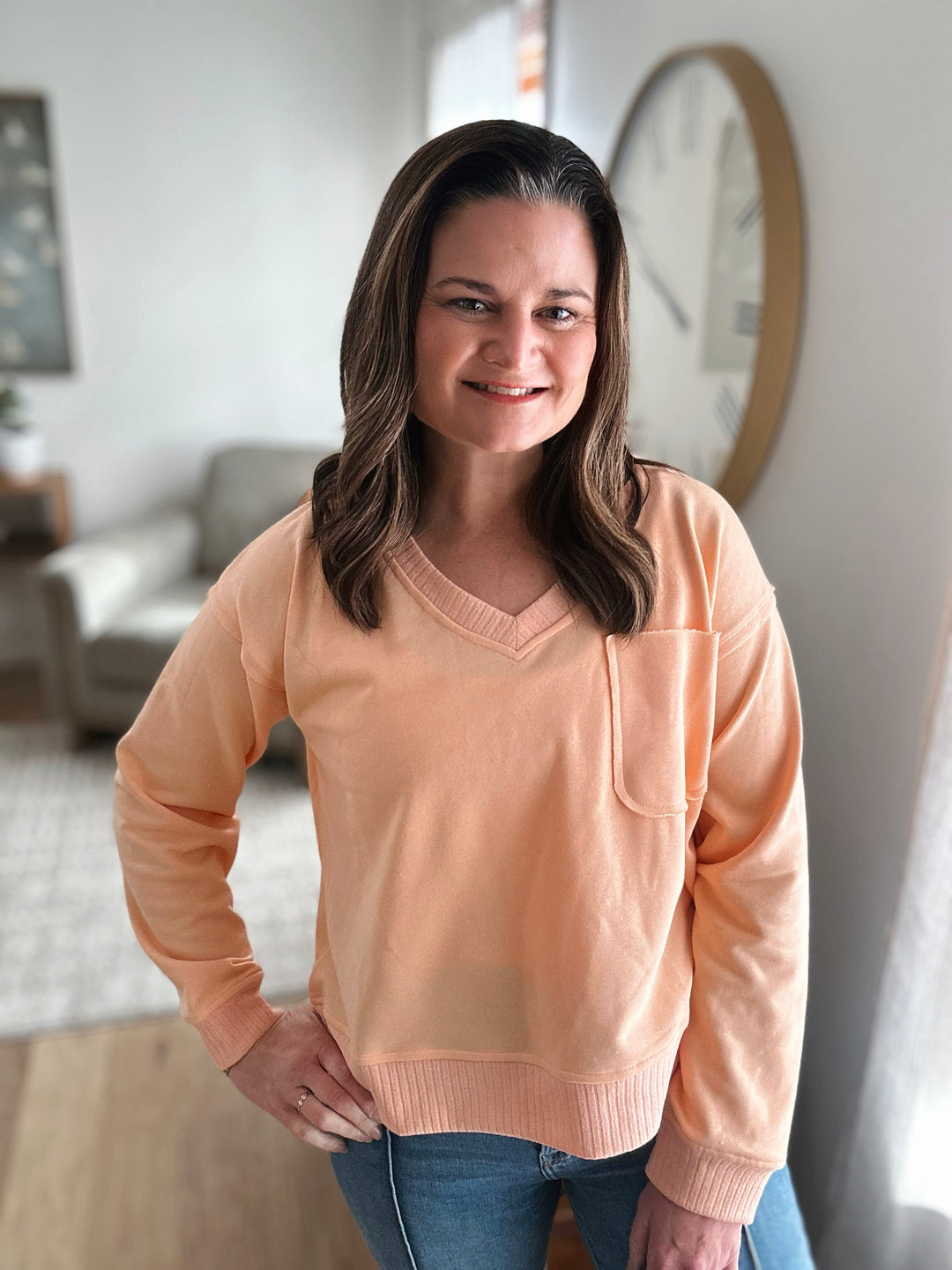 Woman wearing a peach sweater in a living room setting