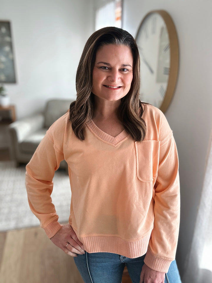 Woman wearing a peach sweater in a living room setting