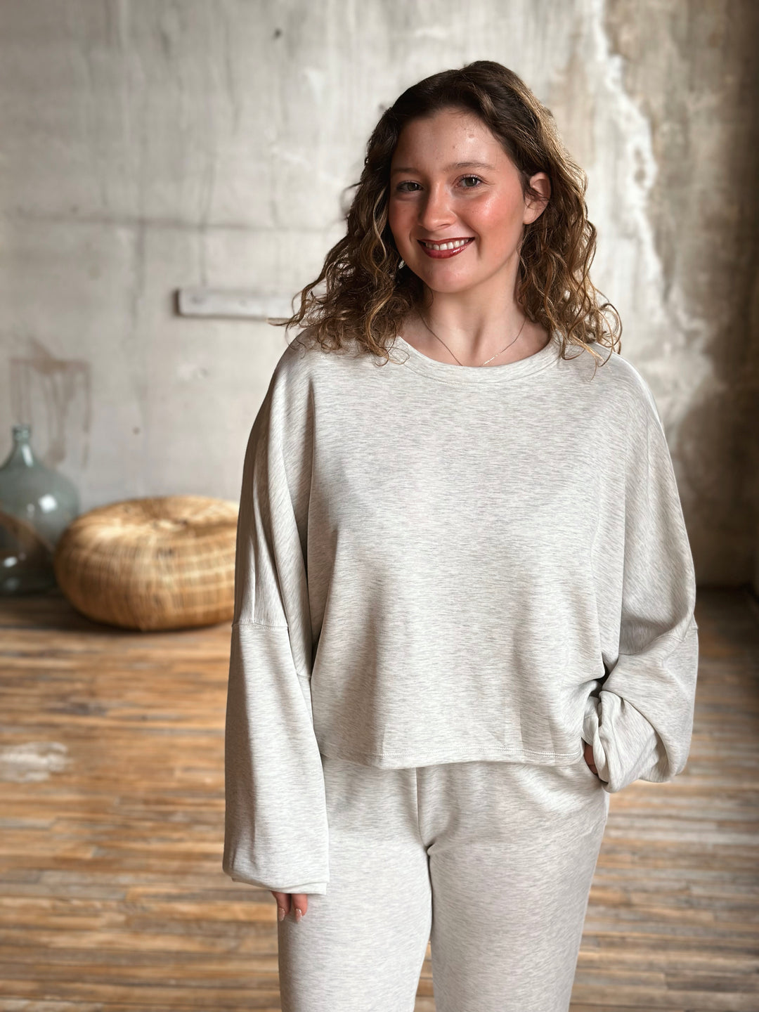 Woman wearing a light grey outfit in a rustic setting