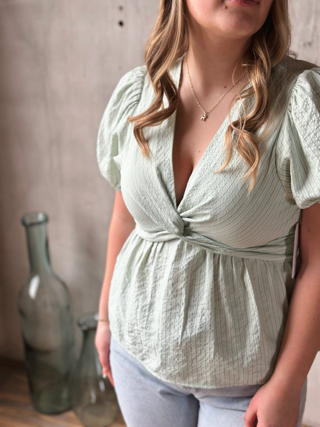 Woman wearing a light green blouse with puffed sleeves against a neutral background