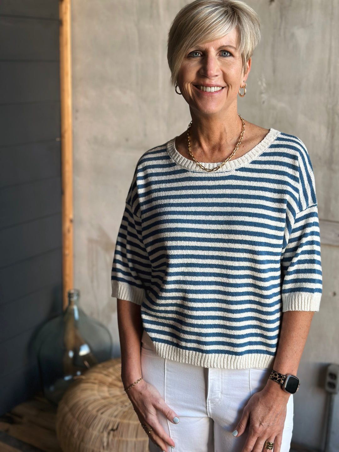 Woman wearing a blue and white striped sweater standing against a neutral background