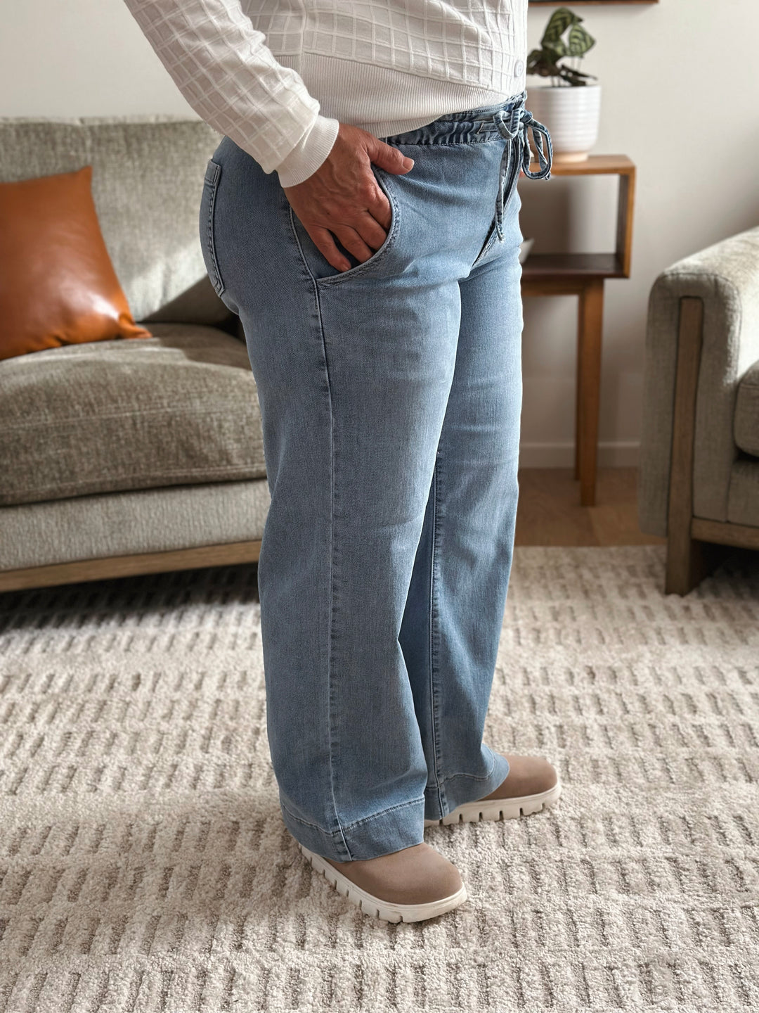 Person wearing light blue jeans standing in a living room.