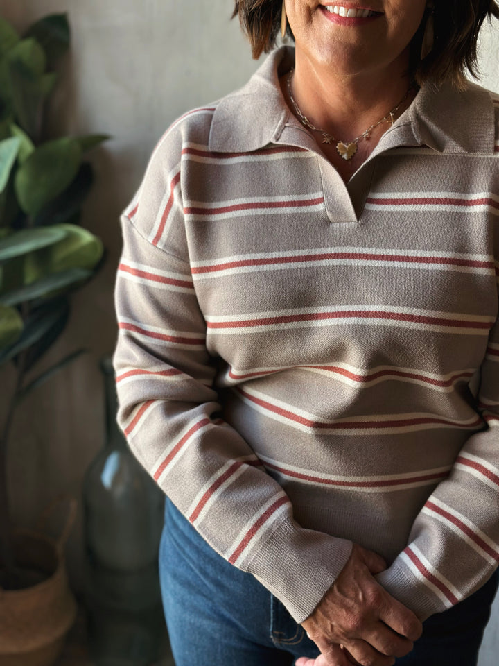 Person wearing a striped sweater with a plant in the background