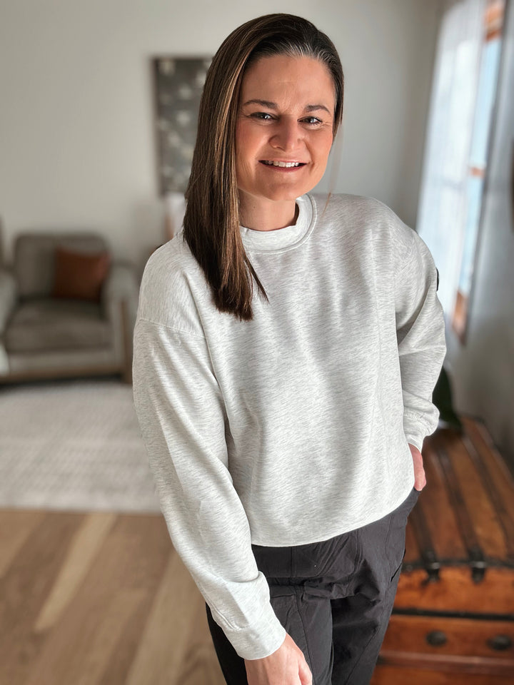 Woman wearing a light gray sweatshirt in a living room setting