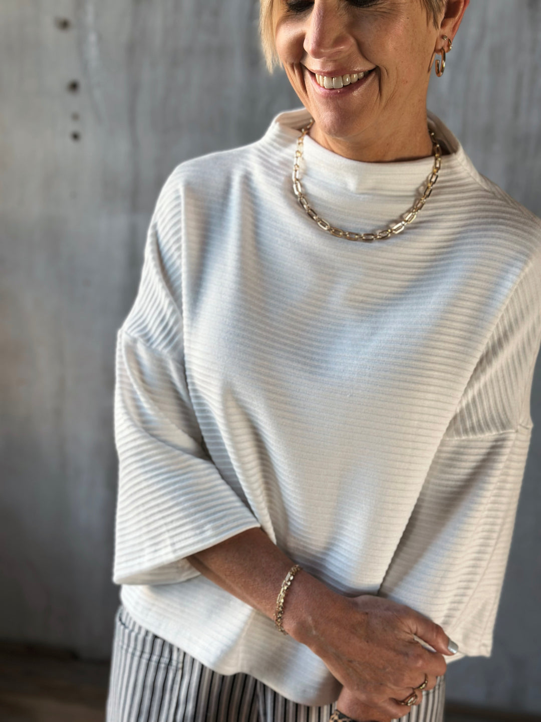 Person wearing a white turtleneck sweater with a neutral background