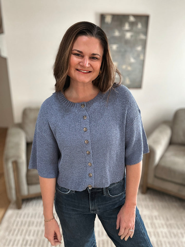 Woman wearing a blue knitted cardigan in a living room setting