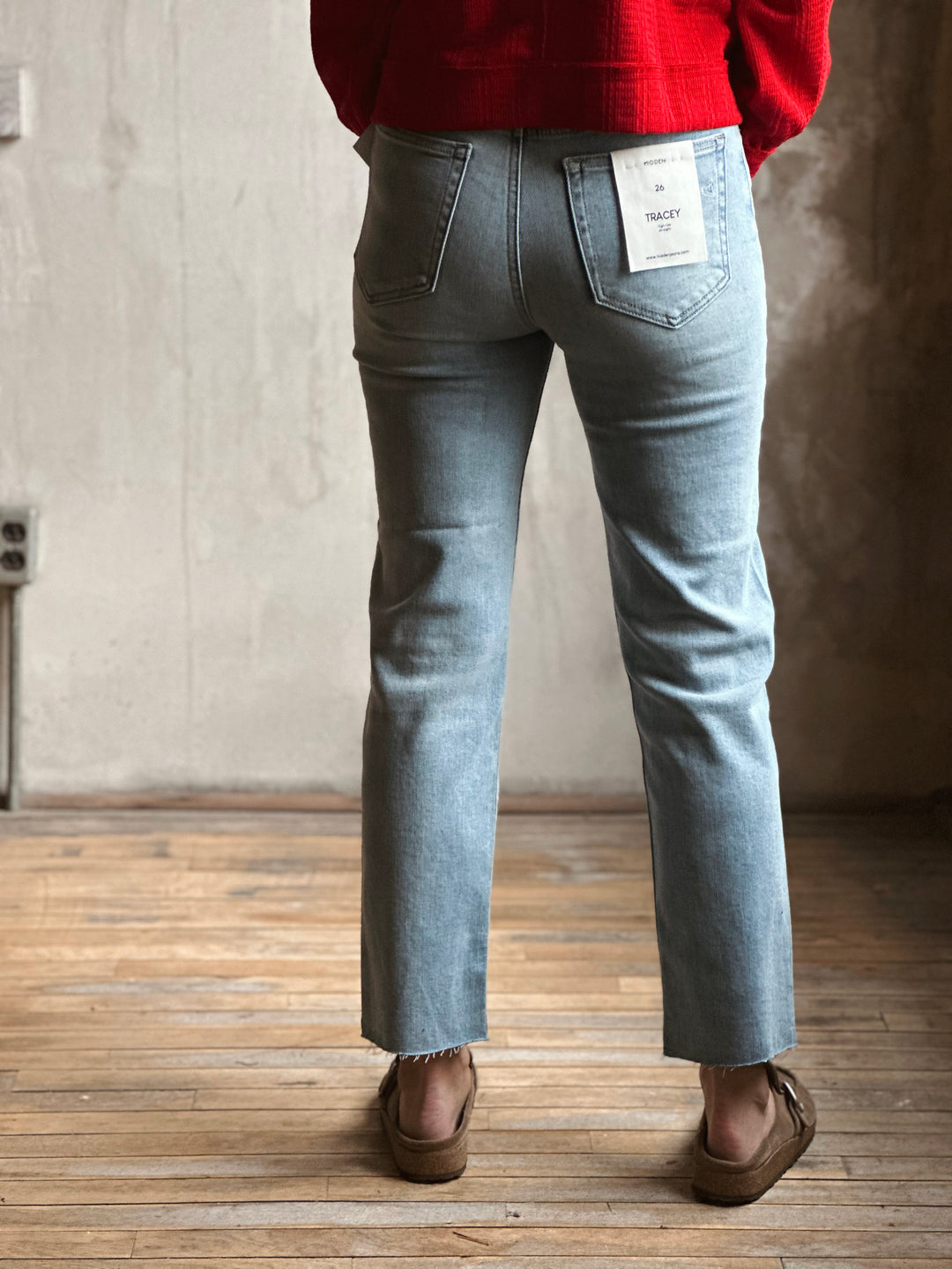 Person wearing light blue jeans with a red sweater in an indoor setting