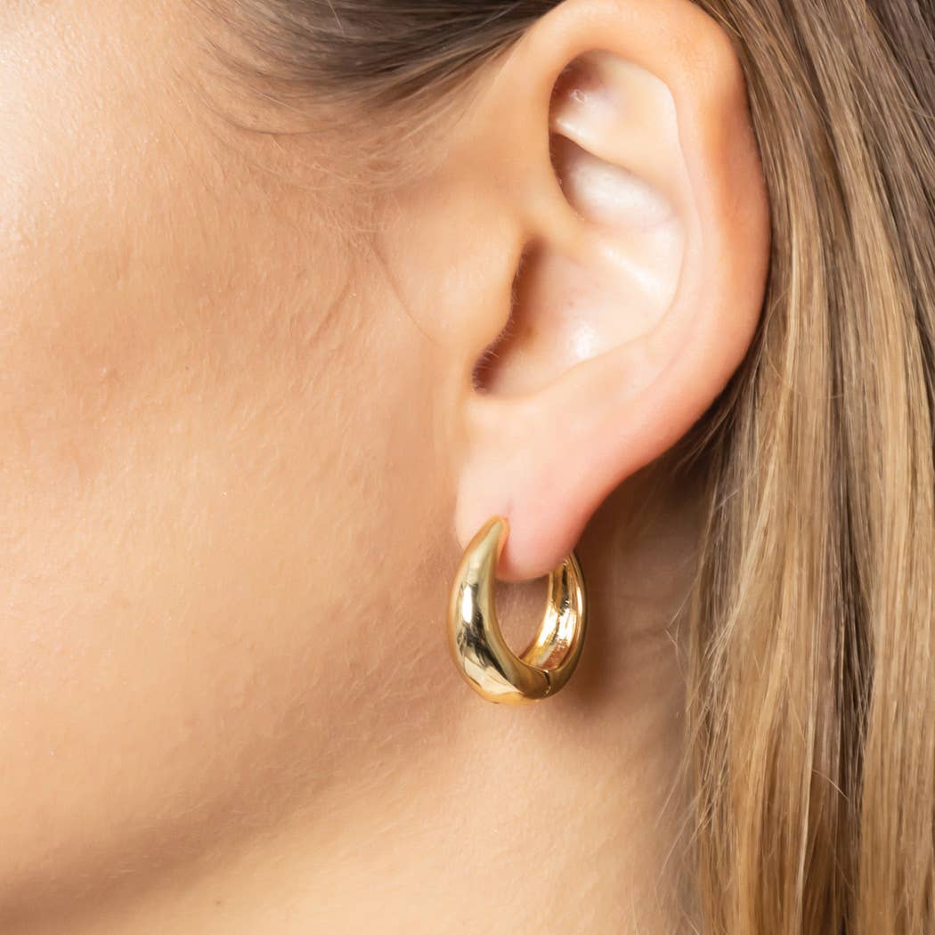 Gold hoop earring worn by a person with blonde hair.