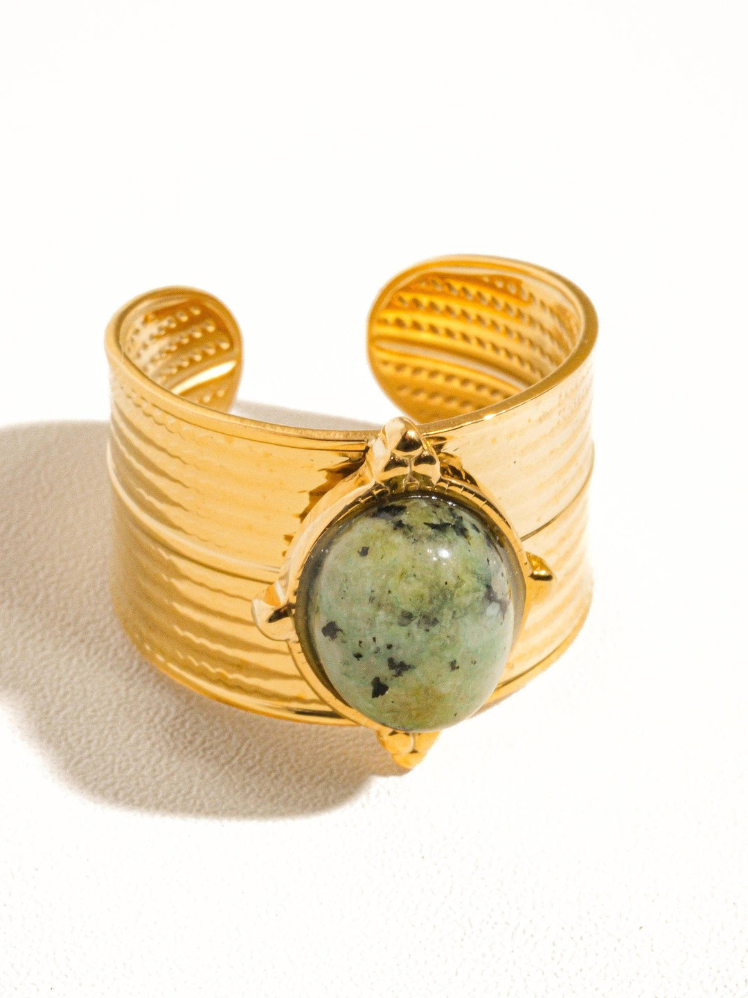 Gold ring with a green stone on a white background
