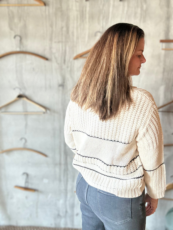 Back view of a cream collared sweater with black stripes