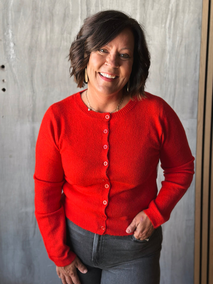 Woman wearing a red cardigan against a gray background