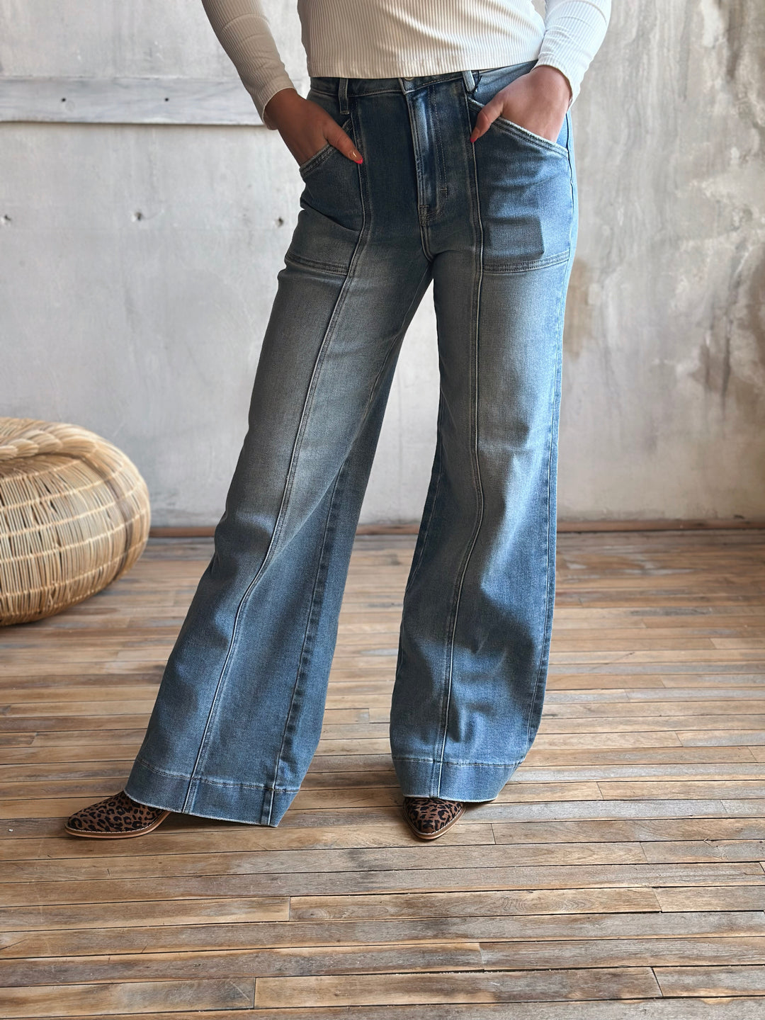A person wearing blue flared jeans with a seam down the middle of the pants legs.