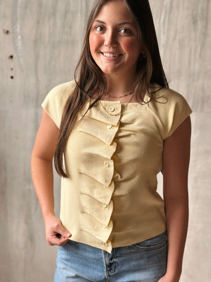 Woman wearing a beige ruffled blouse against a neutral background