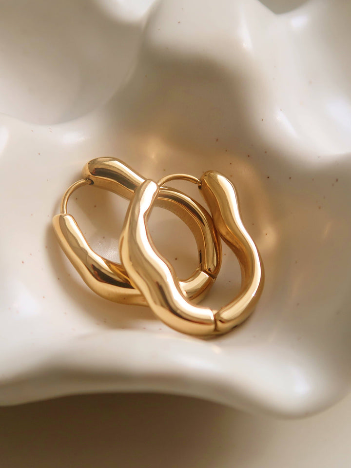 Gold hoop earrings on a textured white surface