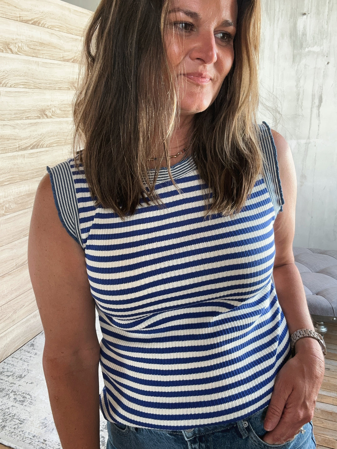 Woman wearing a blue and white striped sleeveless top indoors.