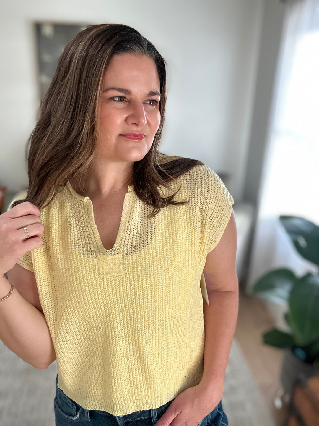 Woman wearing a yellow knit top indoors with a neutral background