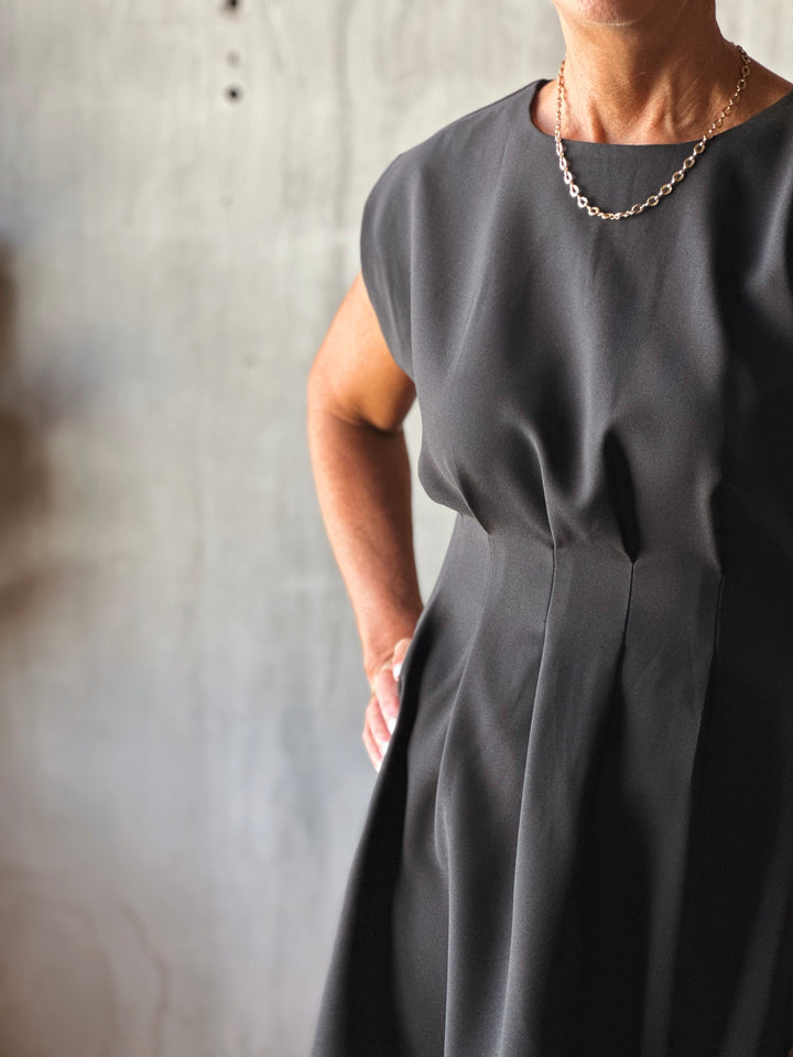 Person wearing a dark gray dress against a neutral background