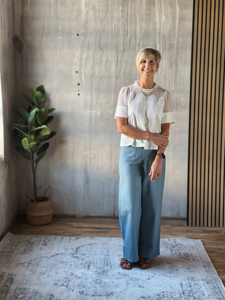 Woman standing in a room with a plant and textured wall