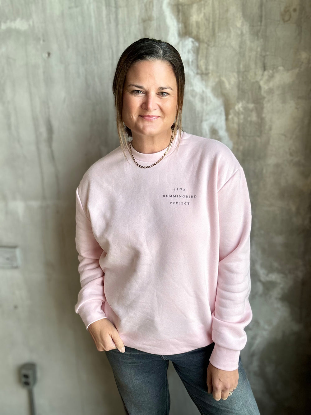 Light pink crewneck sweatshirt worn with jeans, front view