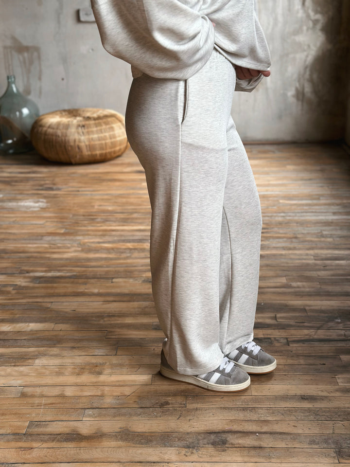 Person wearing a light grey sweat set standing on a wooden floor.