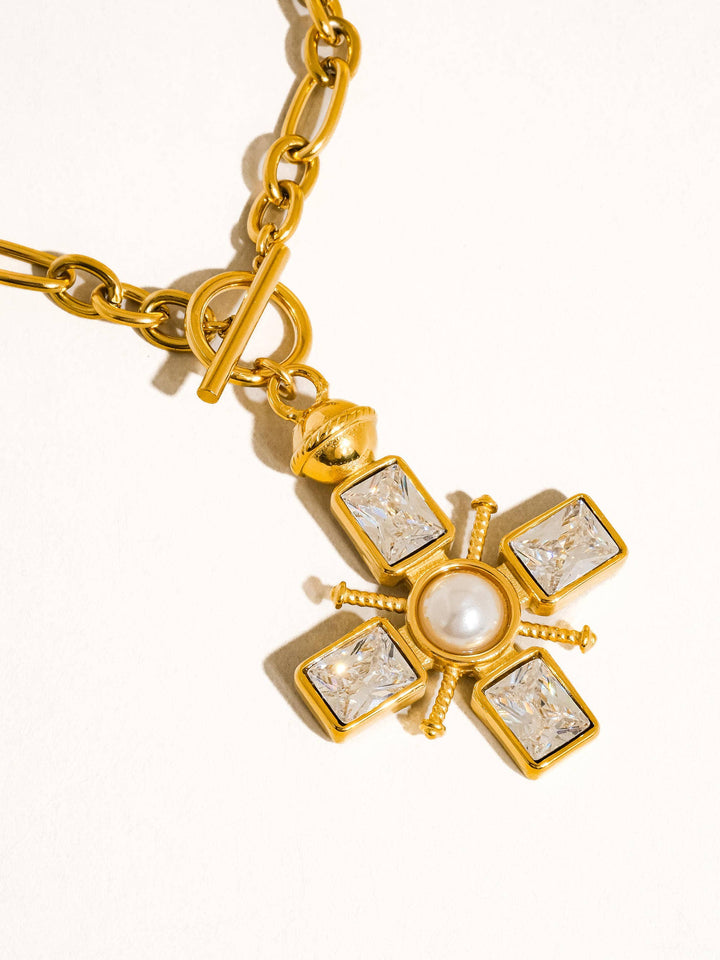 Gold necklace with a star-shaped pendant featuring a central pearl and square gemstones on a white background.