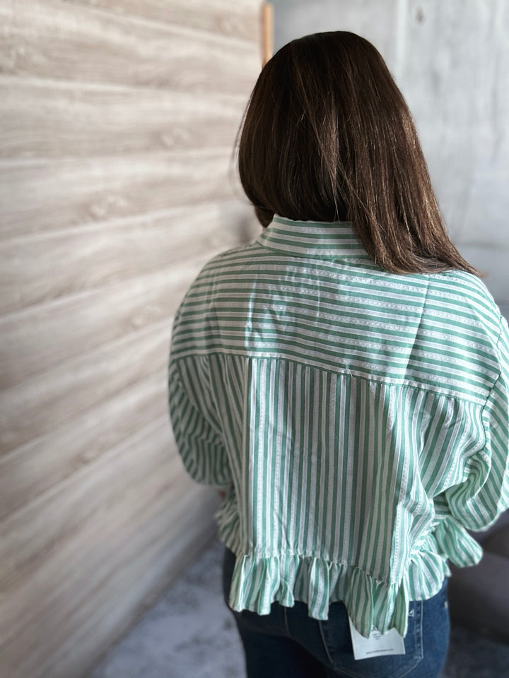 Person wearing a green and white striped shirt against a neutral wall.