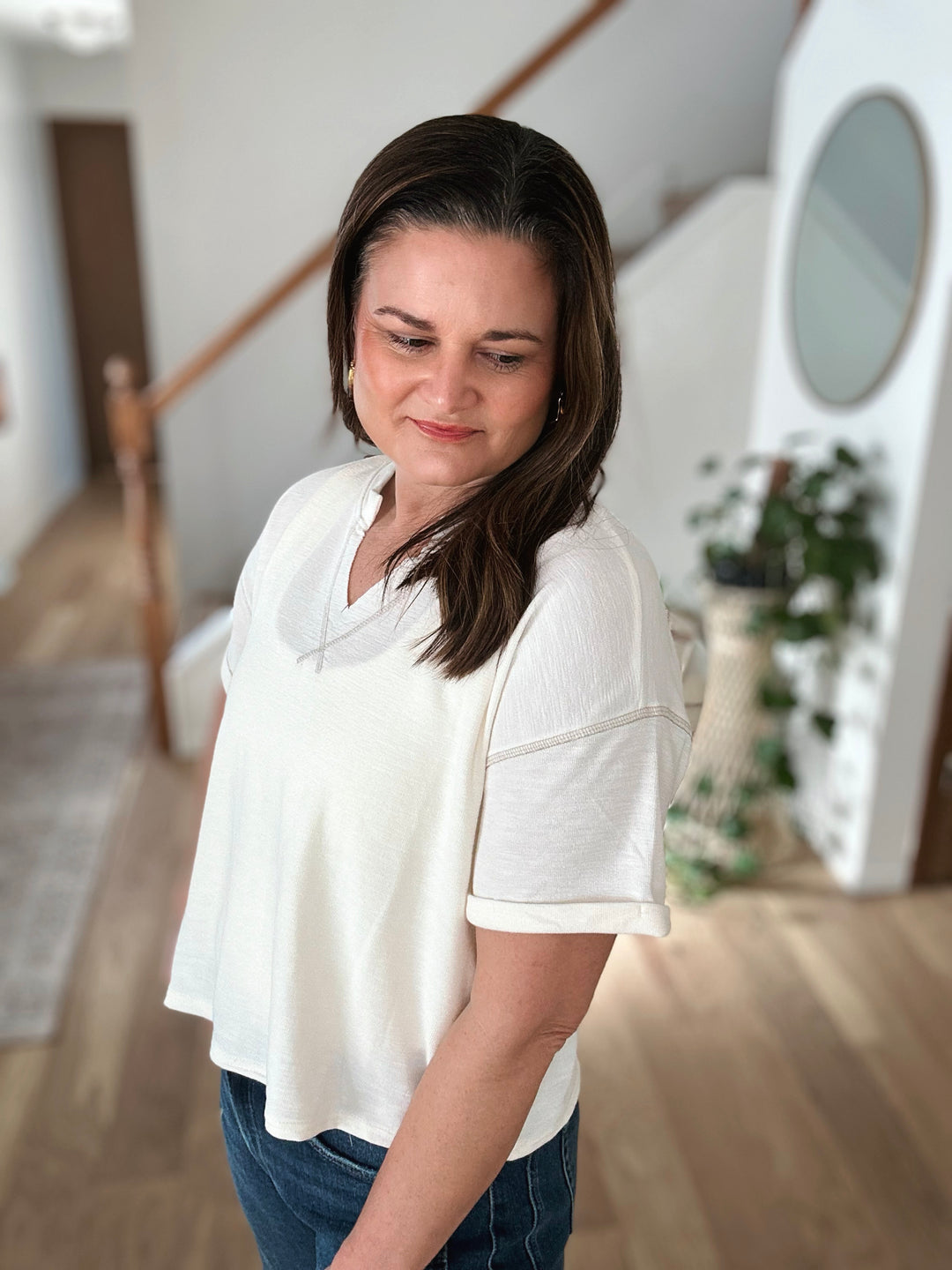 Woman wearing a white t-shirt and blue jeans in a home setting