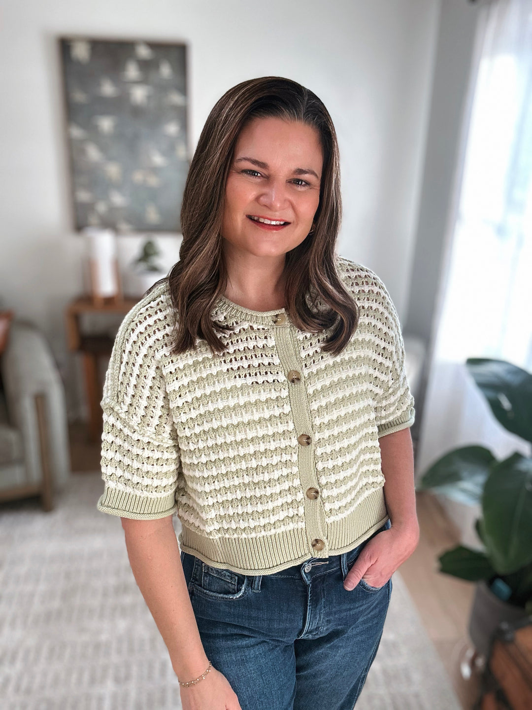 Woman wearing a textured light green cardigan in a home setting